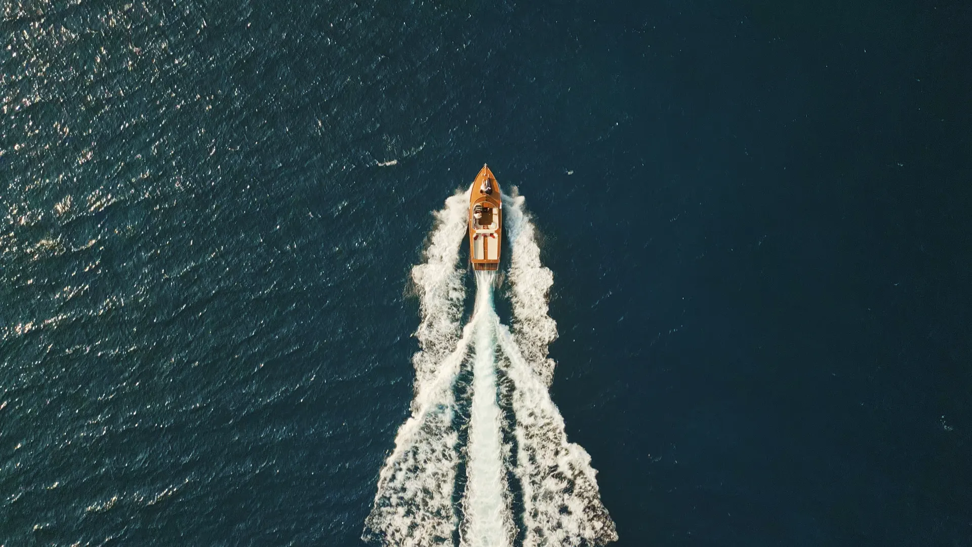 Aerial view of a classic wooden boat crossing the sea on a wedding day in Italy